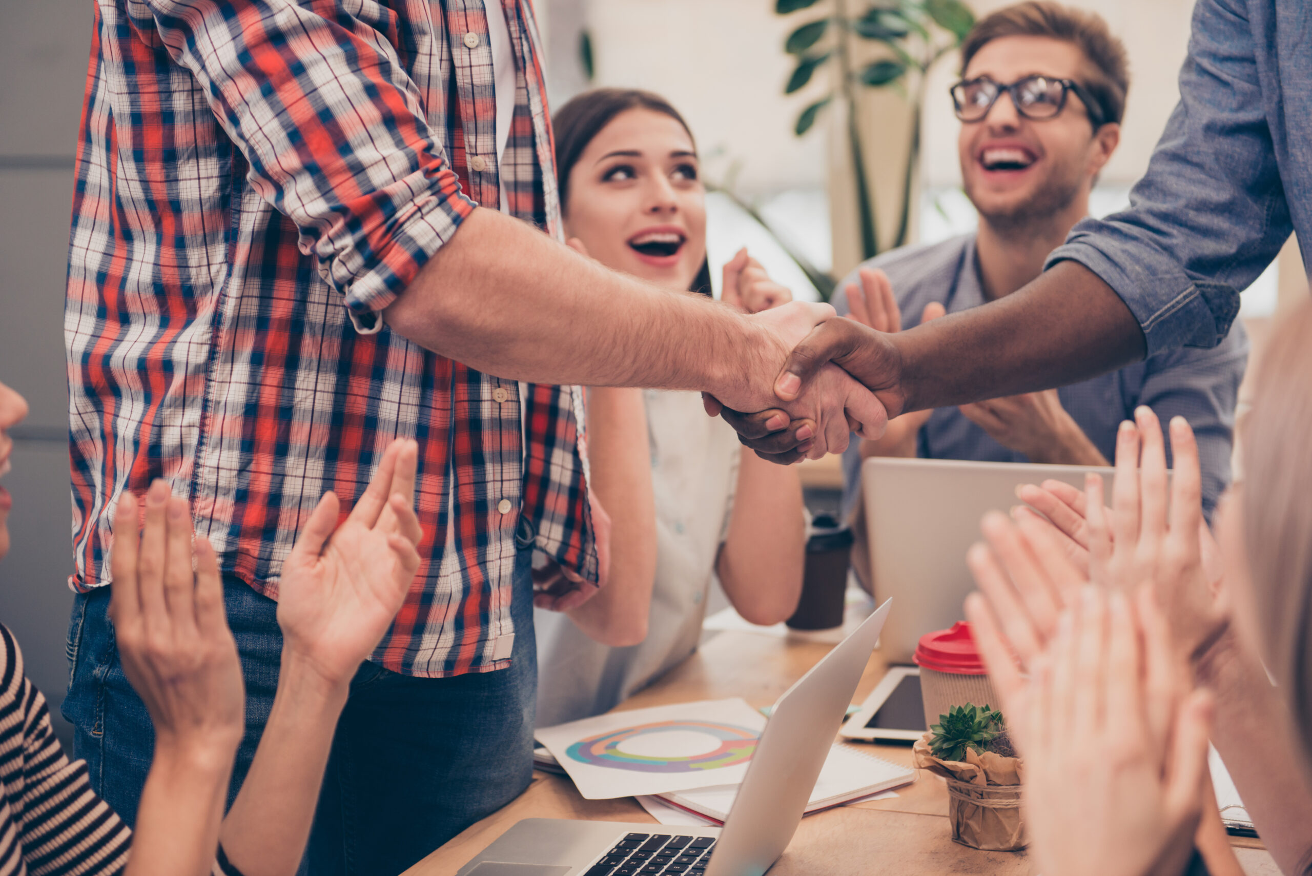 Close up of employees shaking hands during welcome to the team meeting