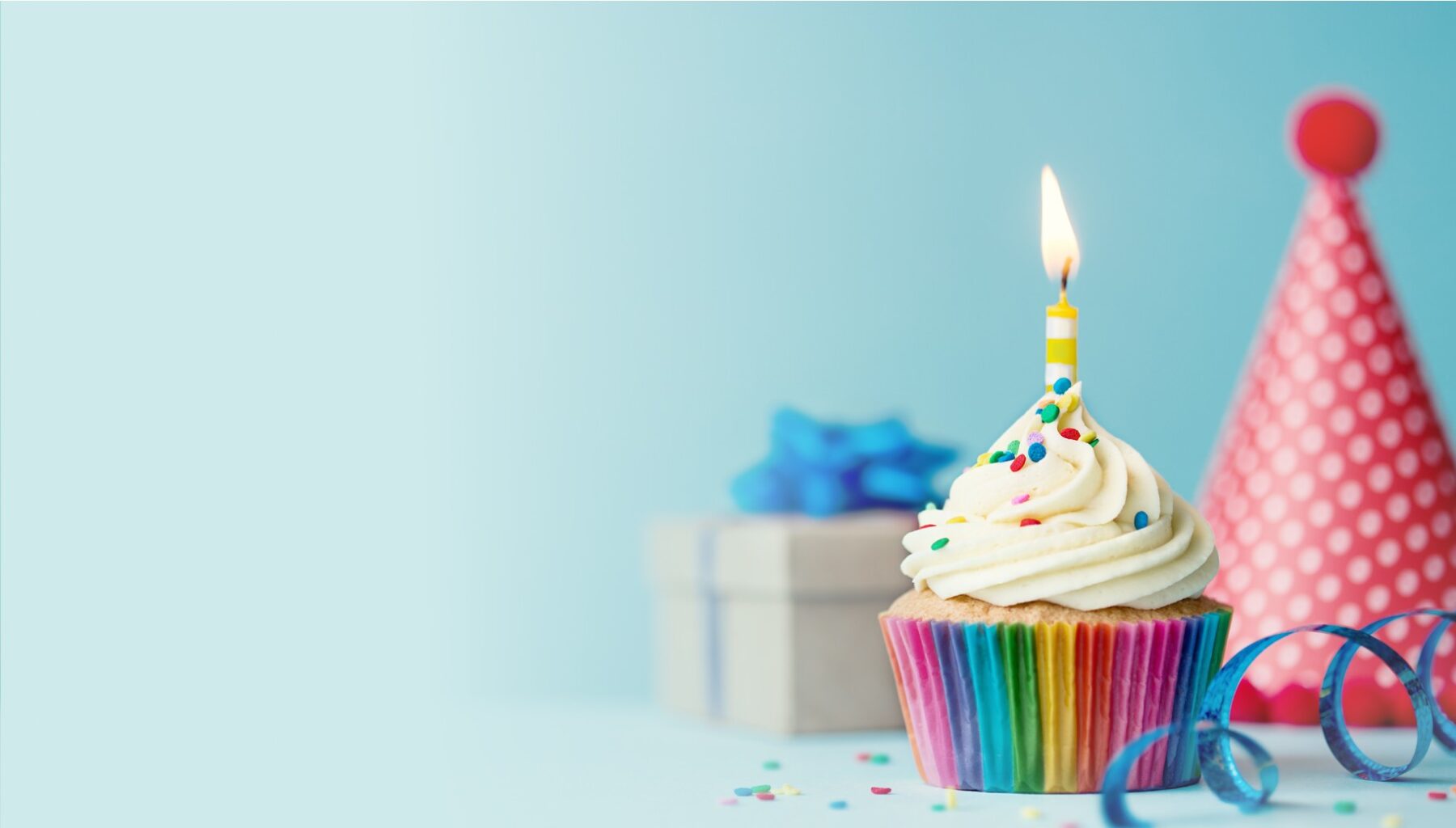 Cupcake with candle, birthday hat, and present