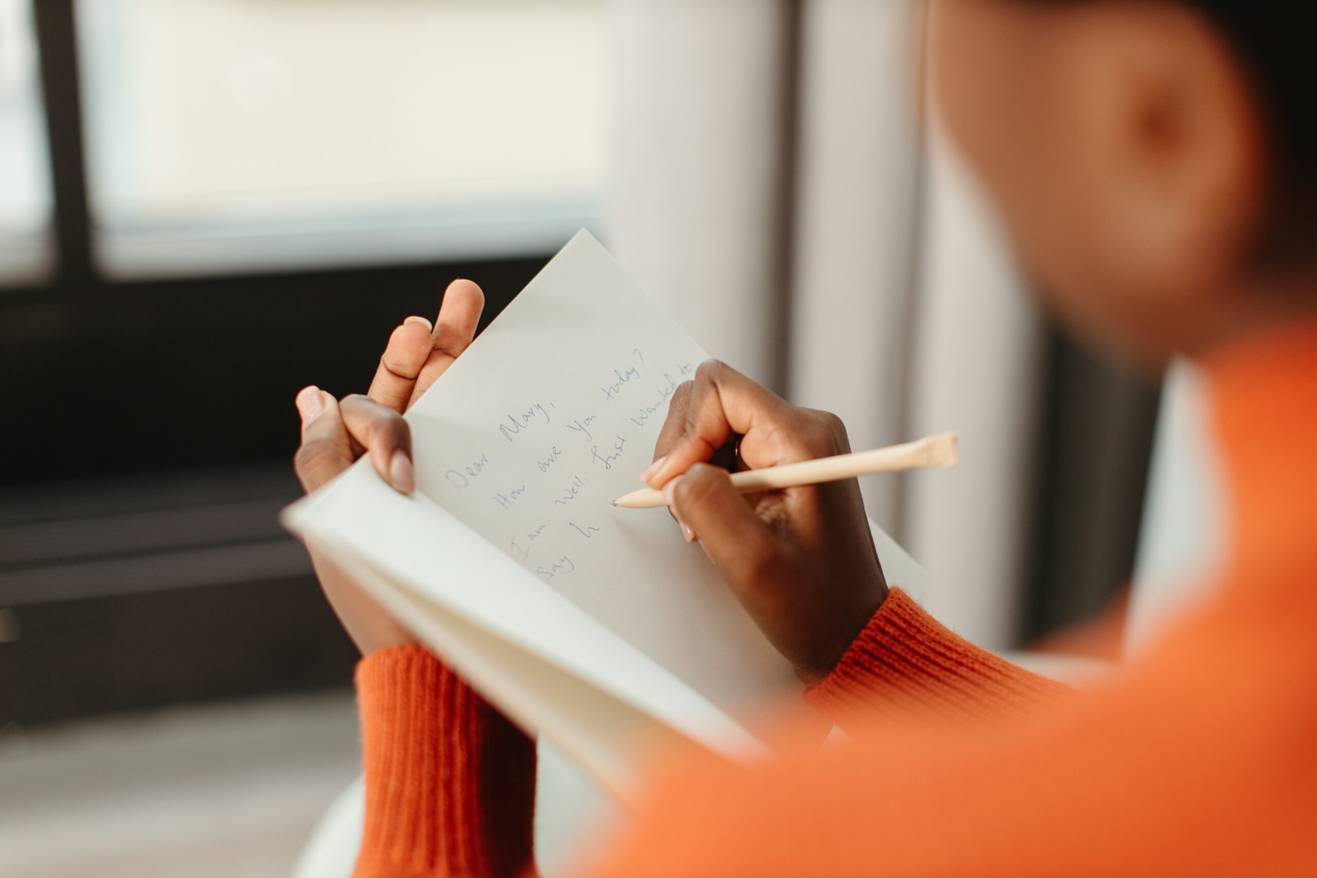 Person writing message inside birthday card