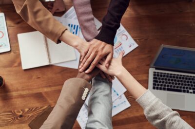 People putting hands together over meeting table